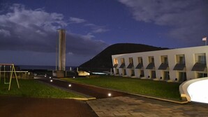 A modern building with a long, narrow tower, a paved walkway, and a grassy area. - Pousada de Angra do Heroismo - Forte Sao Sebastiao (Angra do Heroismo)