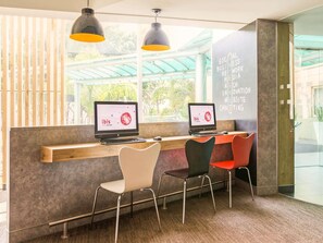 Un espacio de trabajo con dos computadoras, una silla blanca, una silla negra y una silla roja.