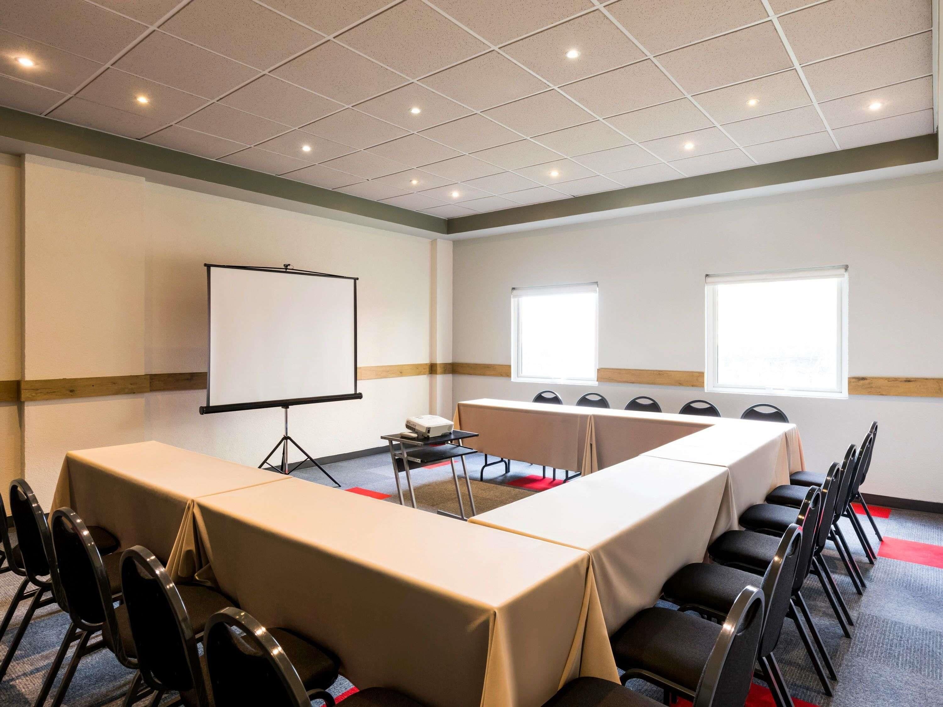 A conference room with a long table, chairs, a projector, and a whiteboard.