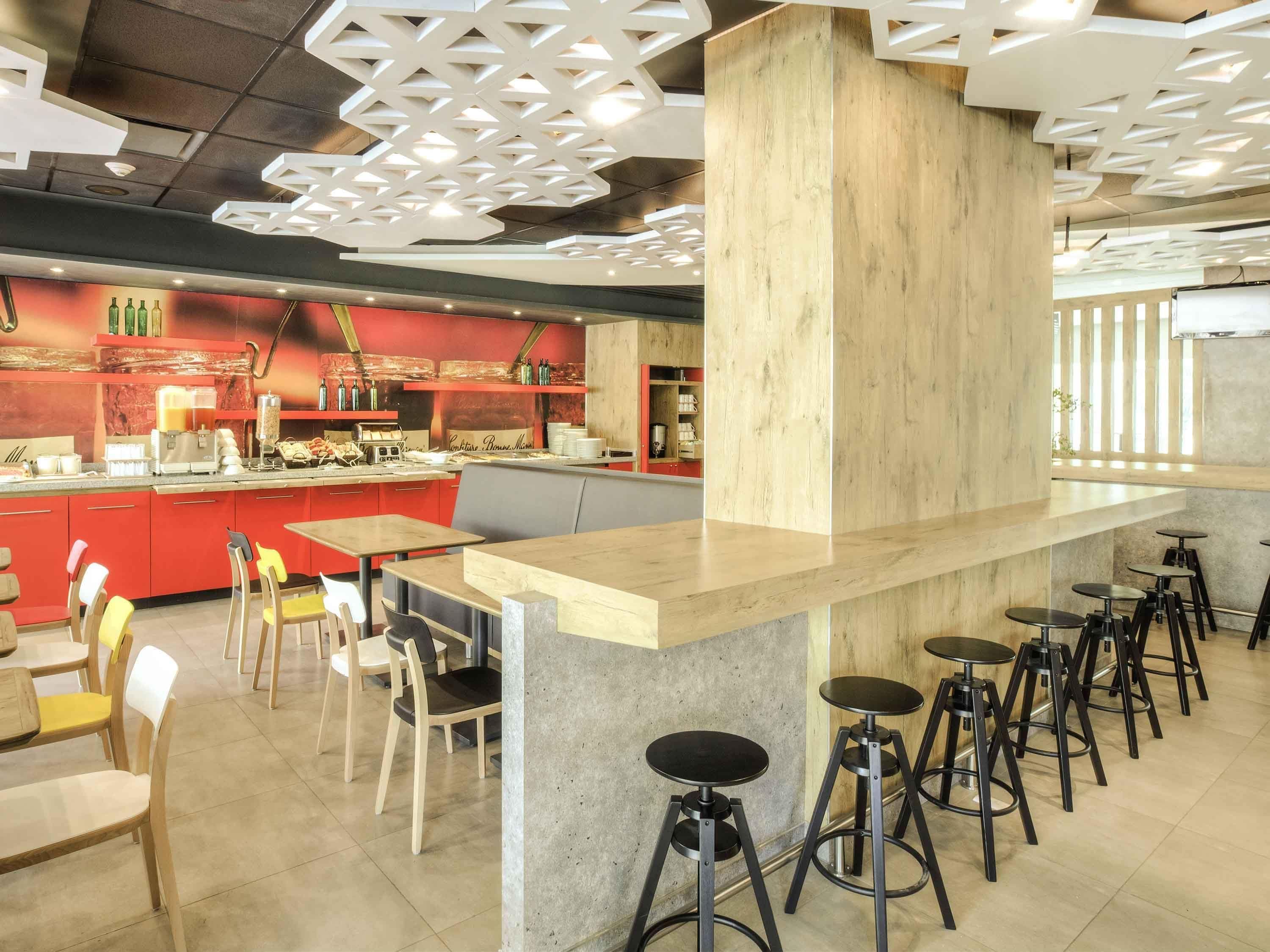 A modern cafe with a central bar area, seating arrangements, and a distinctive ceiling design.