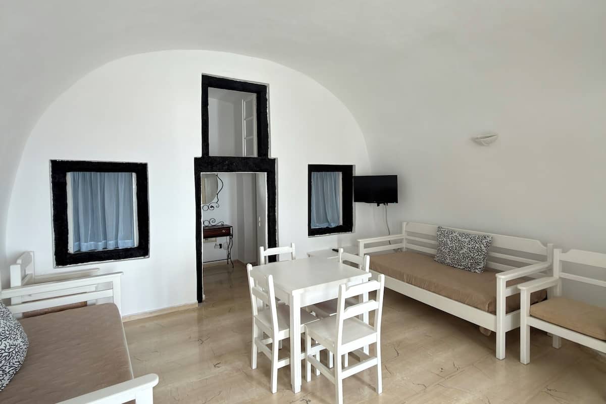 Una habitación con una mesa y sillas blancas, un sofá, una cama y un techo curvo.
