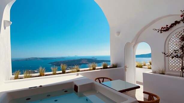A modern outdoor hot tub area with a clear view of the sea and distant islands. - Nomikos Villas (Santorini)