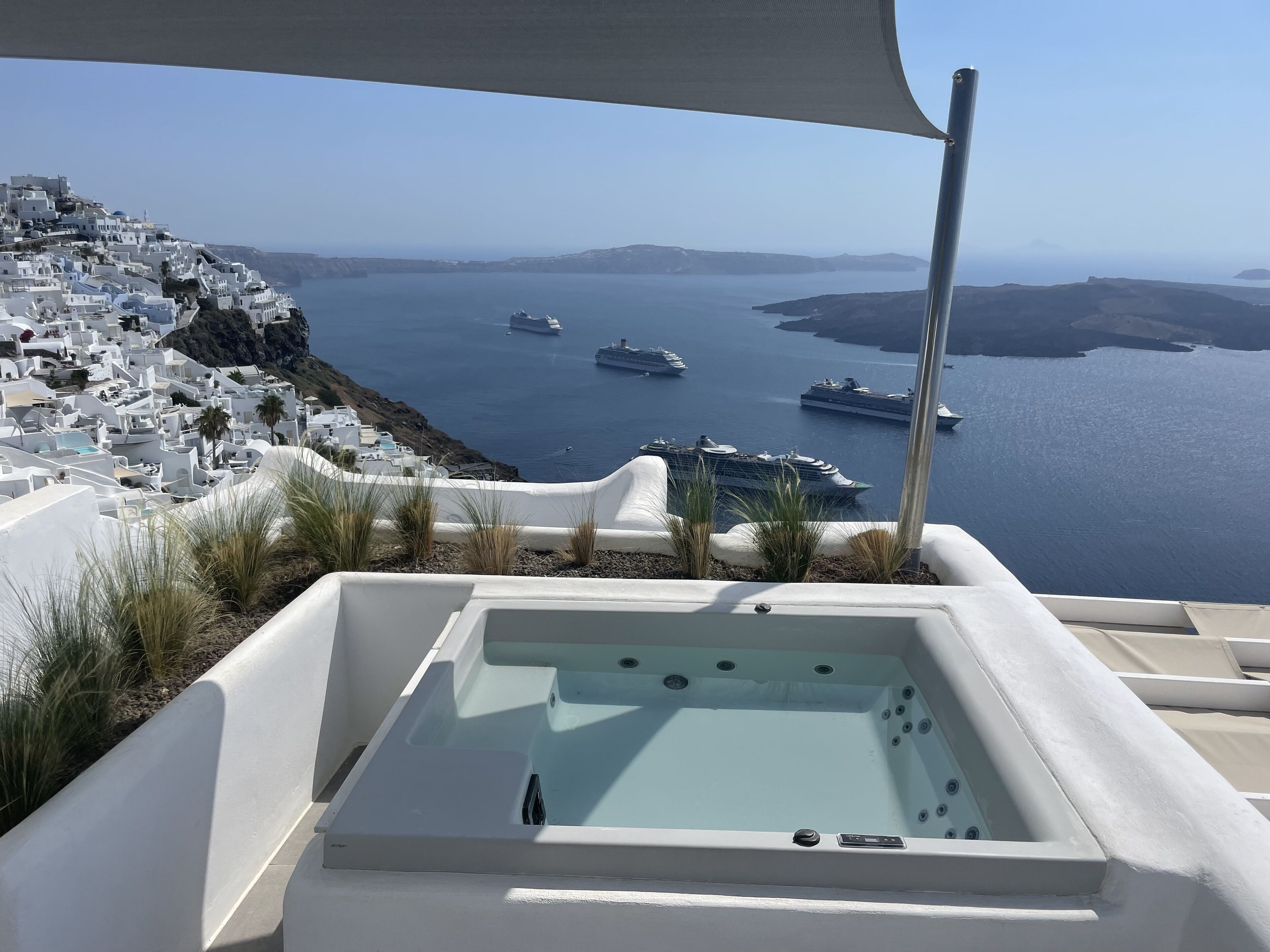 A hot tub with a clear view of a coastal town and ships in the background.