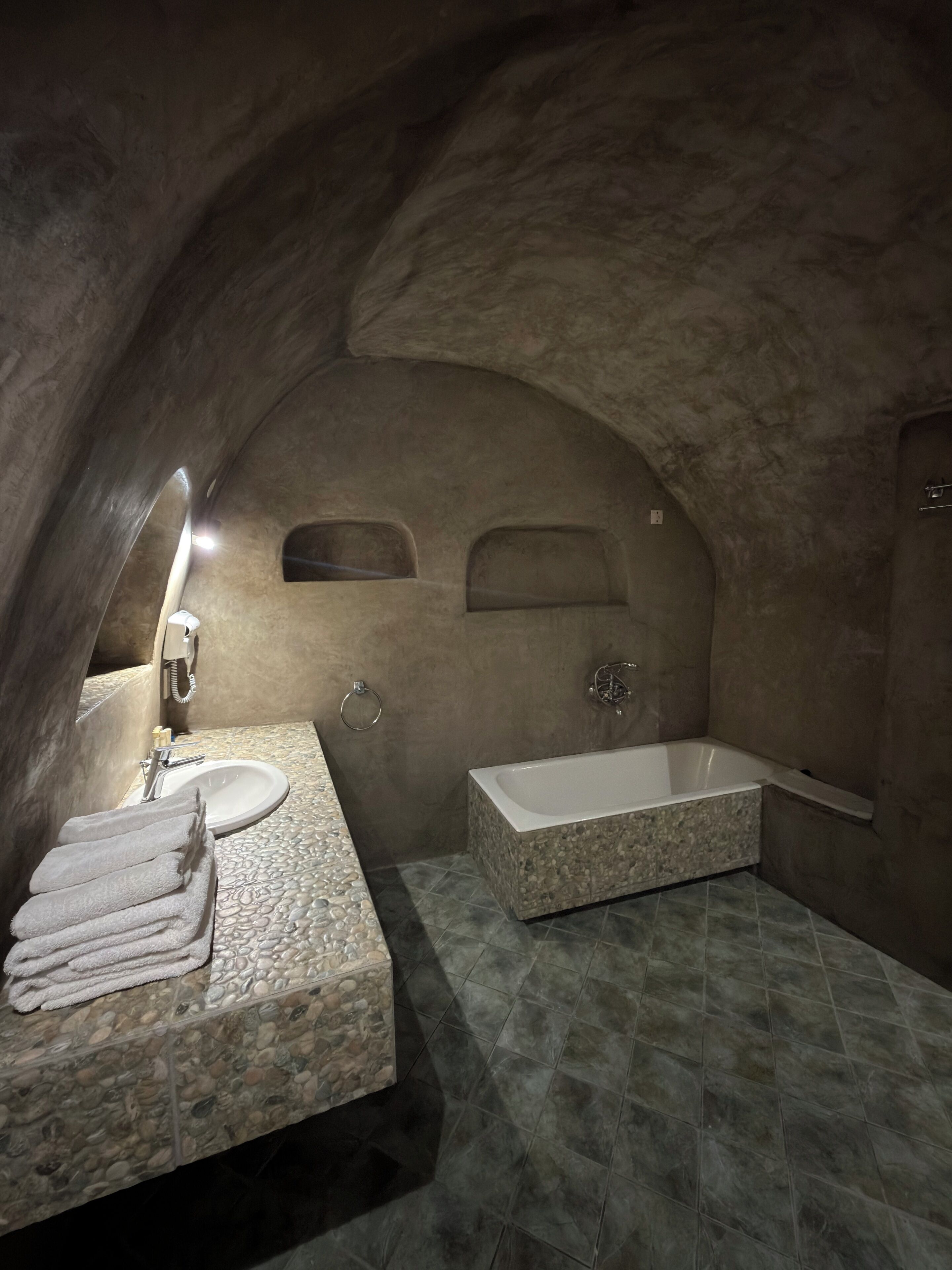 Un baño con lavamanos de piedra, una bañera y un espejo.