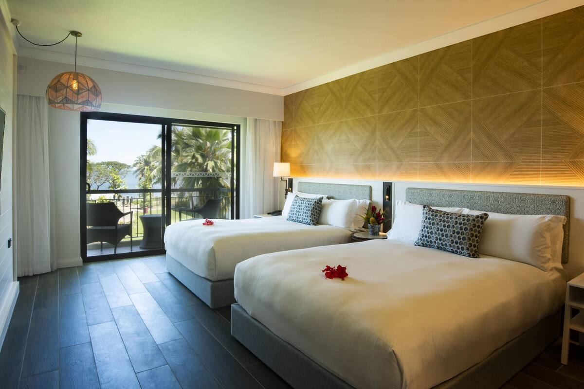 Une chambre d’hôtel avec deux lits, un balcon offrant une vue agréable et un plafond décoré de motifs.