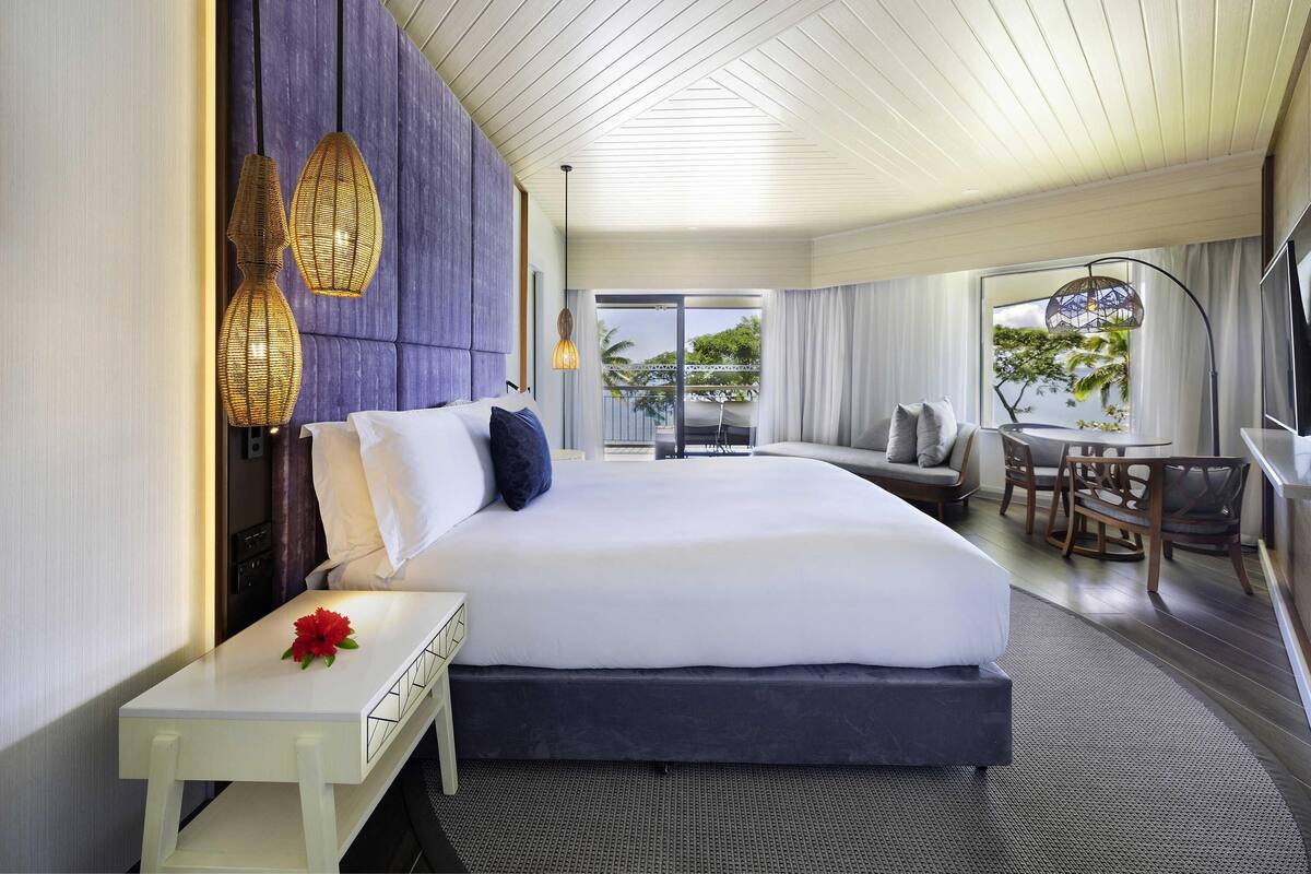 Une chambre d’hôtel moderne dotée d’un grand lit, d’un coin repas et d’un balcon avec vue.
