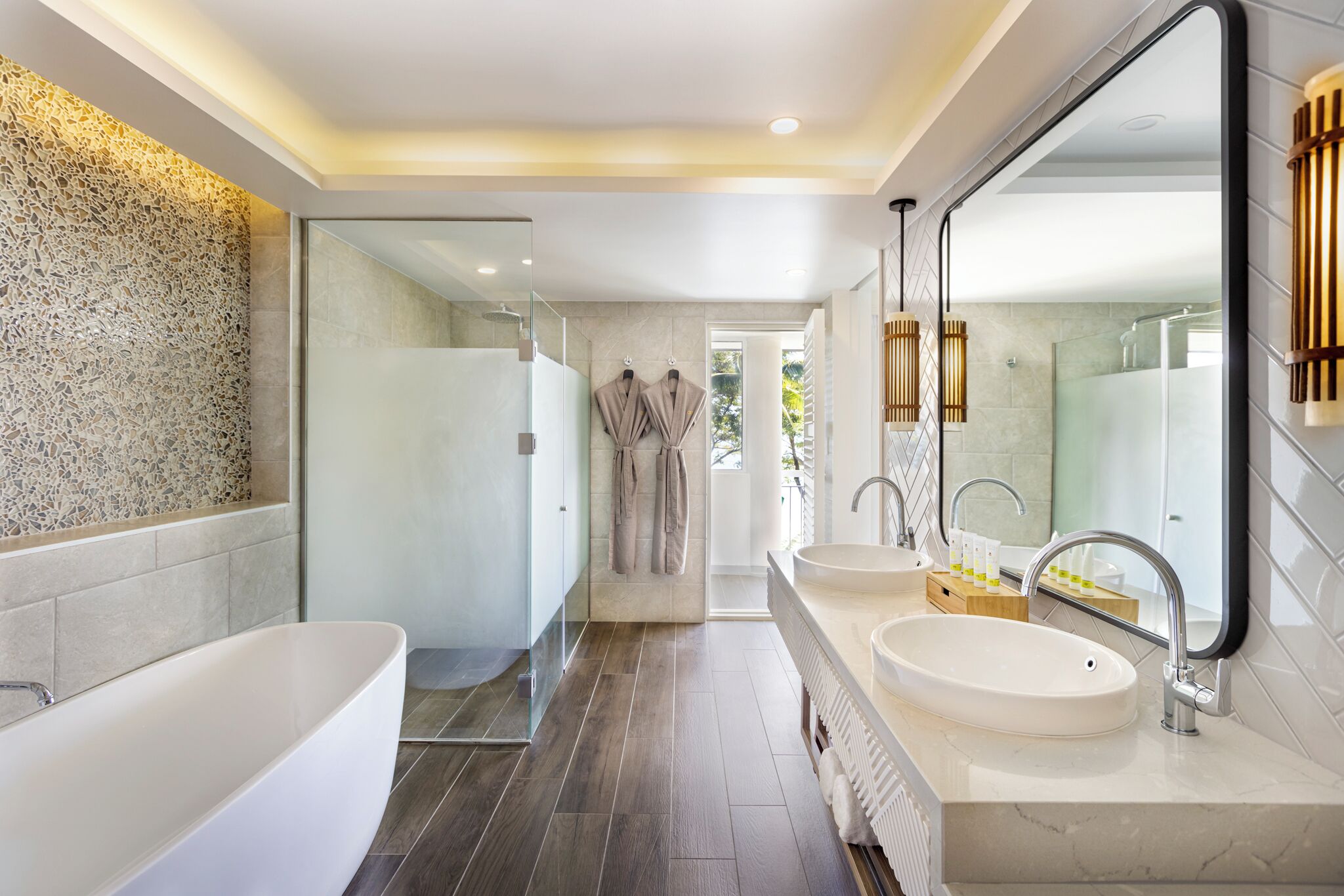 Ein modernes Badezimmer mit einer freistehenden Badewanne, zwei Waschbecken, einem großen Spiegel und einer Duschkabine.