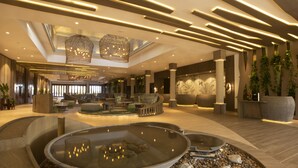 A spacious lobby with a central water feature, seating areas, and modern lighting.