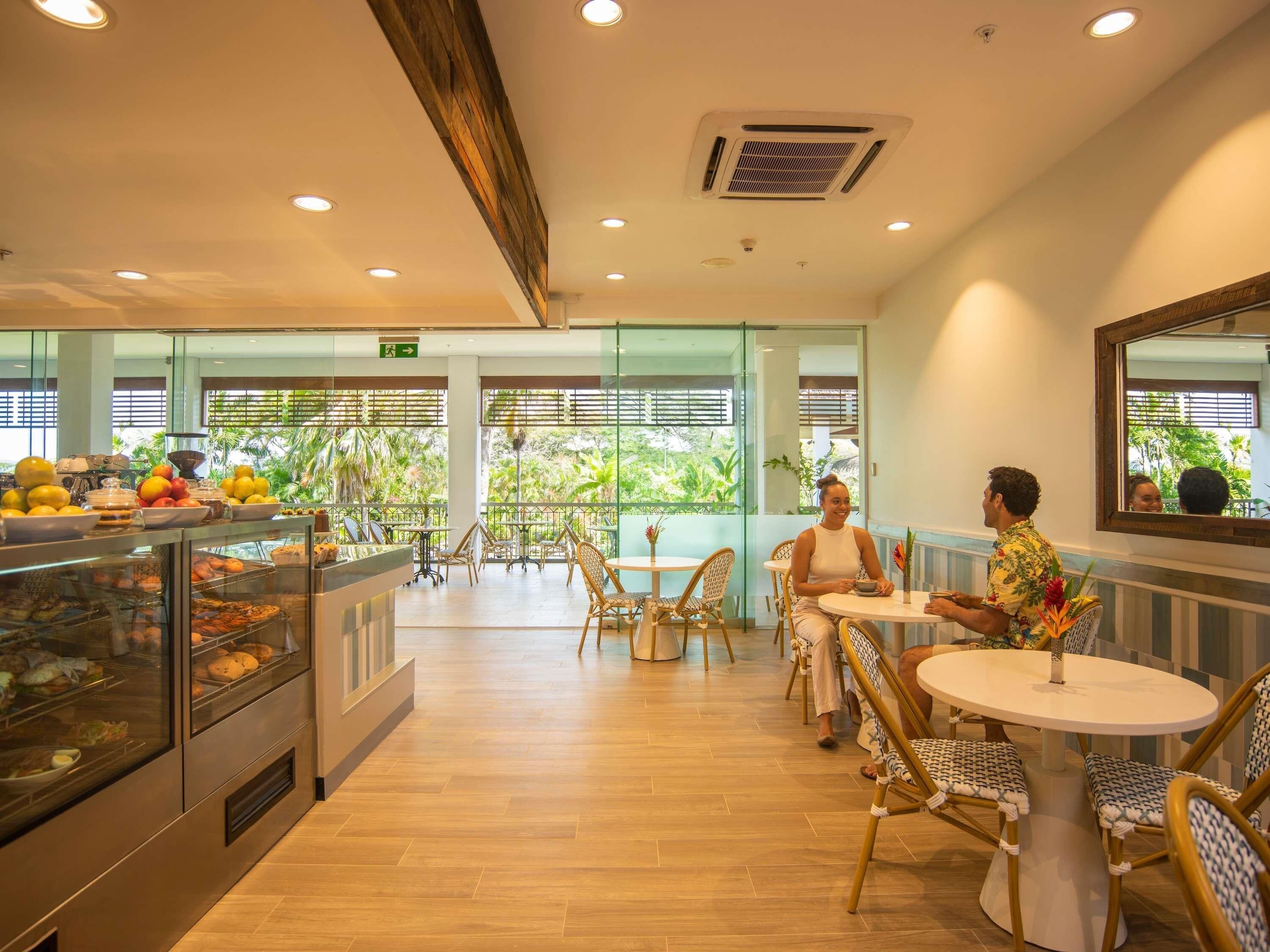 A restaurant with a buffet, outdoor seating, and a view of greenery.