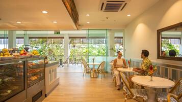 A restaurant with a buffet, outdoor seating, and a view of greenery.