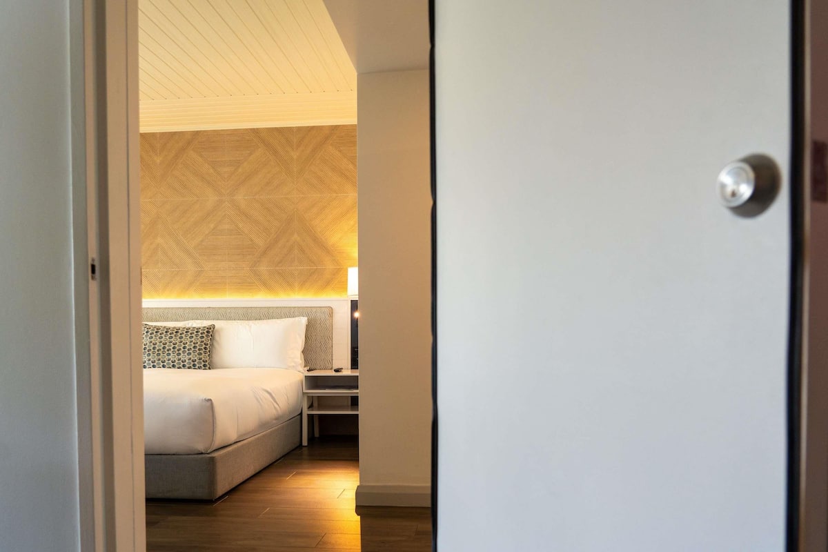 A hotel room with a bed, bedside table, and a patterned wall.
