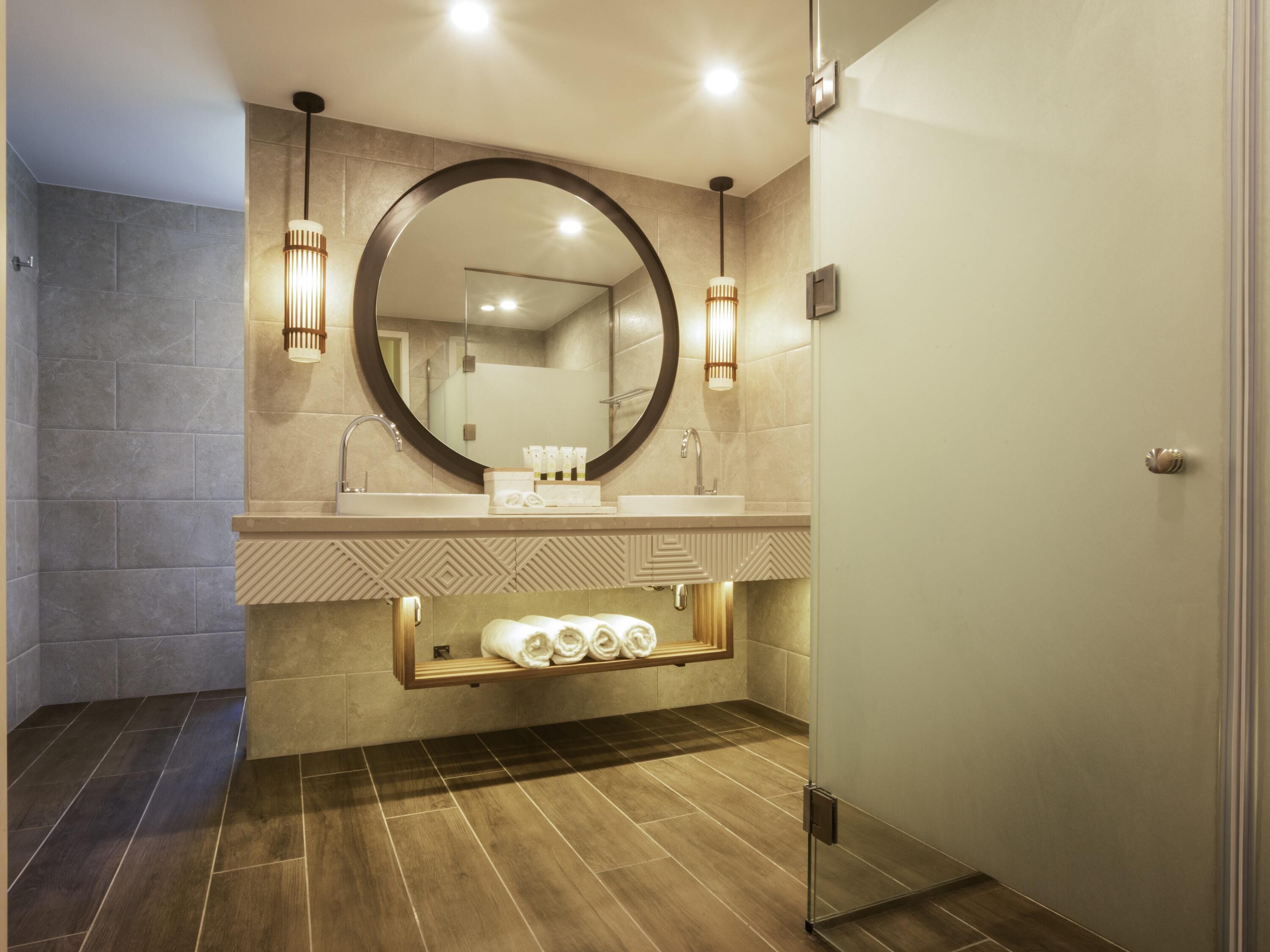A modern bathroom with a large mirror, dual sinks, and a towel rack.