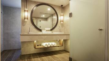 Un baño moderno con un espejo grande, lavamanos dobles y un perchero para toallas.