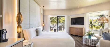 A modern hotel room with a large bed, a TV, a dining area, and a balcony with a view.