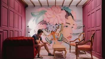 Una habitación con un gran mural floral, un sofá rojo, una mesa de madera y dos sillas de madera.