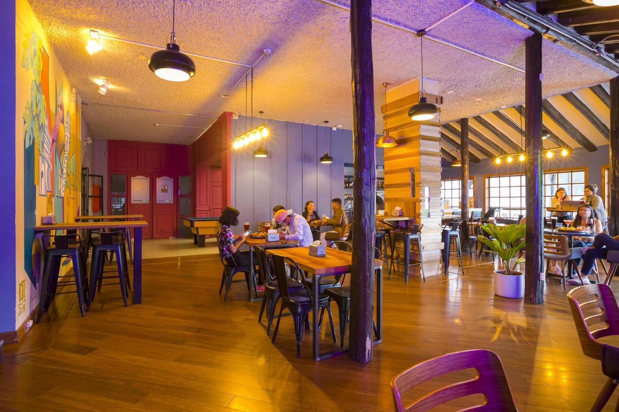 Una cafetería amplia con pisos de madera, varias zonas de estar y una variedad de mesas y sillas.