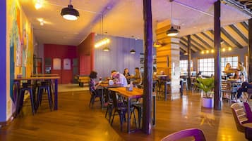 Una cafetería amplia con pisos de madera, varias zonas de estar y una variedad de mesas y sillas.