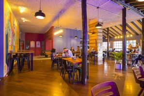 Una cafetería amplia con pisos de madera, varias zonas de estar y una variedad de mesas y sillas.