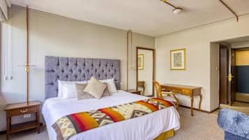 Habitación de hotel con una cama grande, una mesita de noche, un escritorio y una silla.