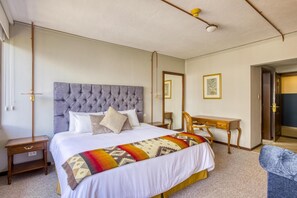 Habitación de hotel con una cama grande, una mesita de noche, un escritorio y una silla.
