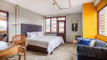 Een hotelkamer met een bed, een bureau, een stoel, een bank en een raam met uitzicht.