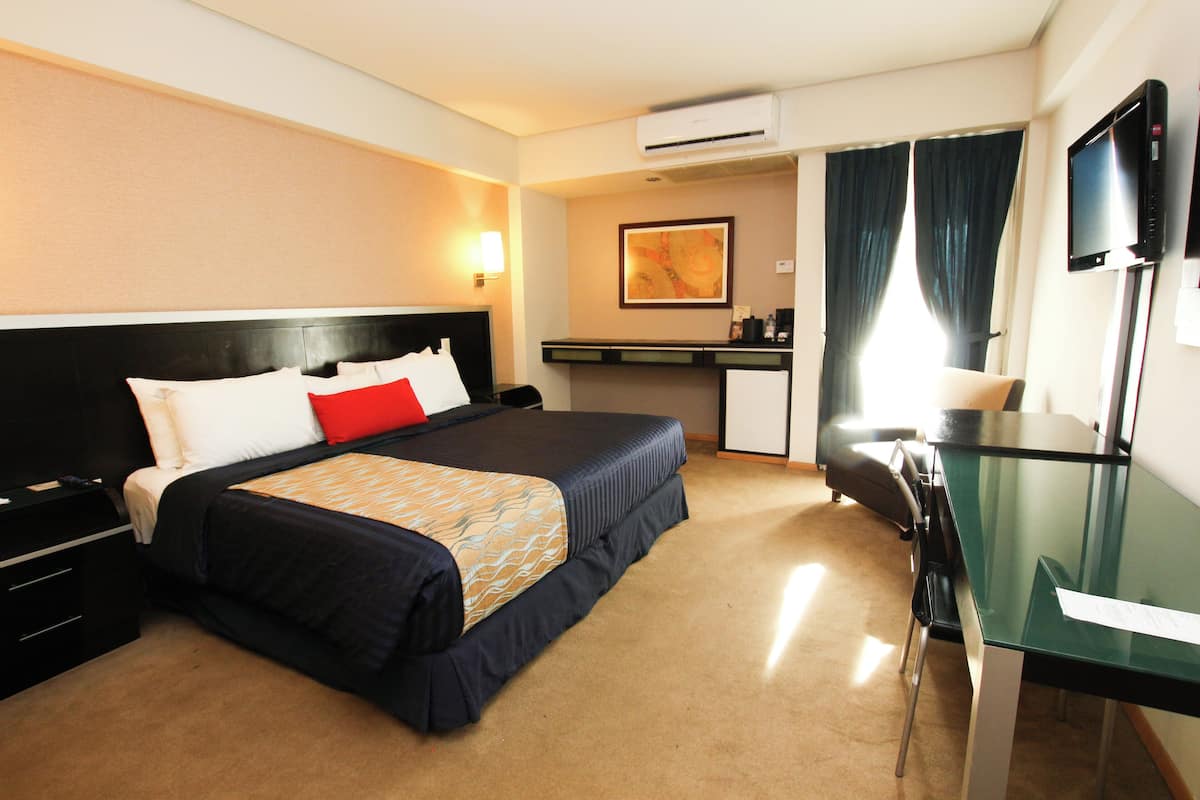 Ein Hotelzimmer mit Bett, Schreibtisch, Stuhl und einem Flachbildfernseher.