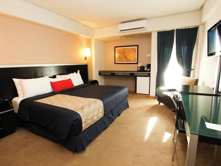 Habitación de hotel con cama, escritorio, silla y televisor de pantalla plana.
