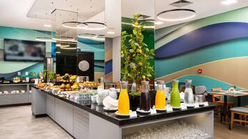 Una barra de desayuno moderna con una variedad de alimentos y bebidas, un televisor de pantalla plana y una planta decorativa.
