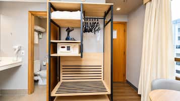 Una cama litera con un panel de control, un tendedero y una mesita en una habitación moderna con vista a un edificio.