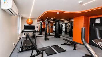 A gym with exercise equipment, treadmills, and a mirrored wall.