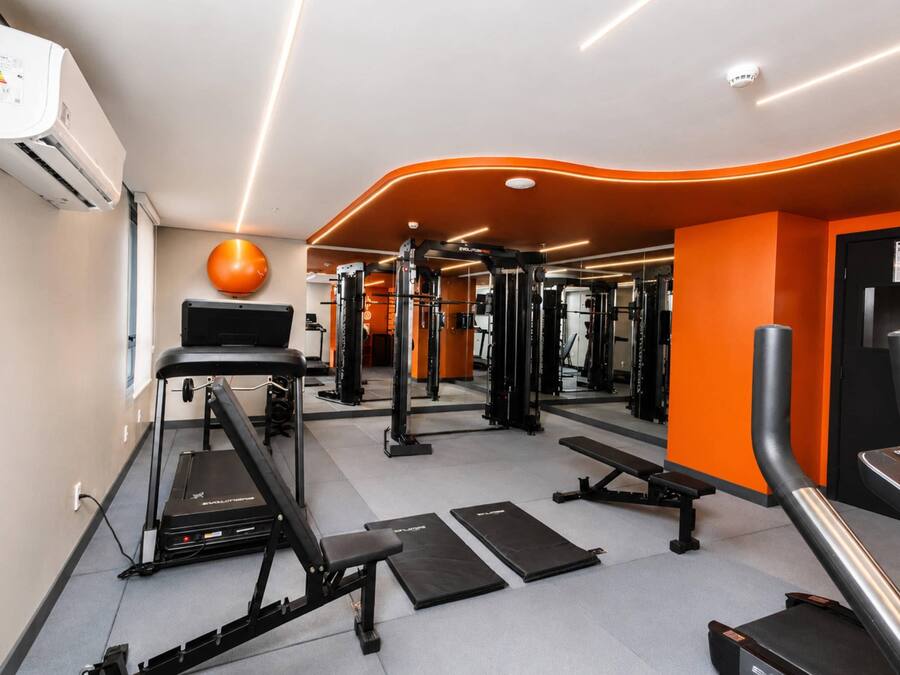 A gym with exercise equipment, treadmills, and a mirrored wall.