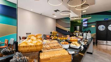 A buffet area with a variety of bread, pastries, and fruits.