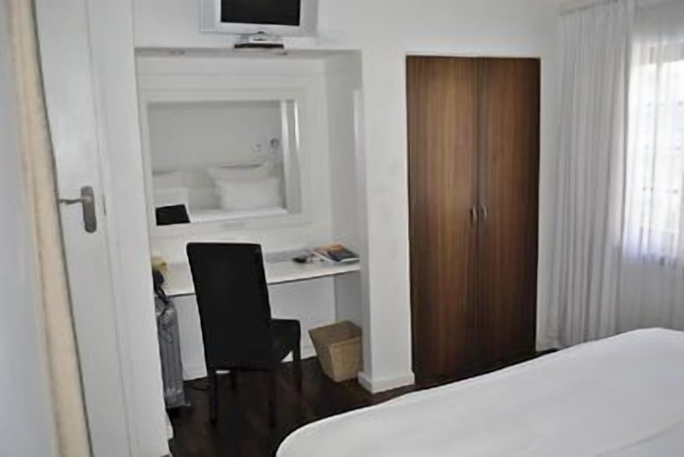 Een hotelkamer met een bed, een bureau met een computer, een stoel en een kledingkast.