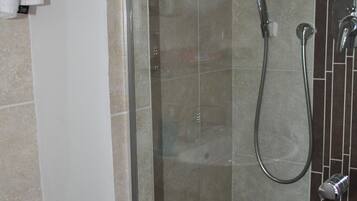 A bathroom with a glass shower enclosure, a purple basin, and a white sink.