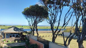 Une propriété résidentielle dotée d’une terrasse, offrant une vue sur la mer et comprenant une pelouse bien entretenue.