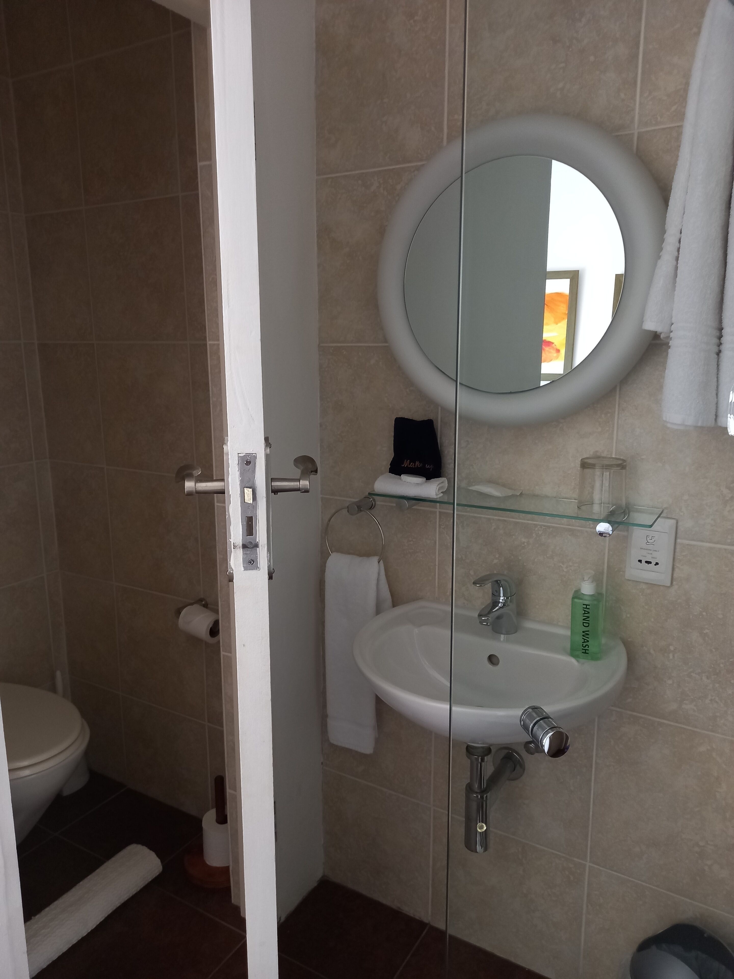 Une salle de bain avec un lavabo blanc, une cabine de douche en verre et un miroir.
