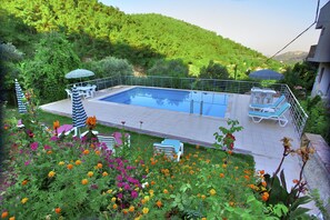 A swimming pool with lounge chairs and umbrellas, surrounded by a garden with various flowers. - Ephesus Boutique Hotel (Kusadasi)