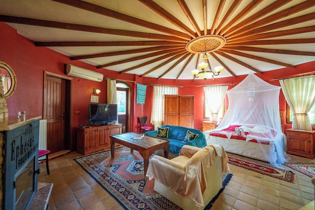 Une pièce avec un plafond en bois, un lit à baldaquin, une télévision et un canapé.