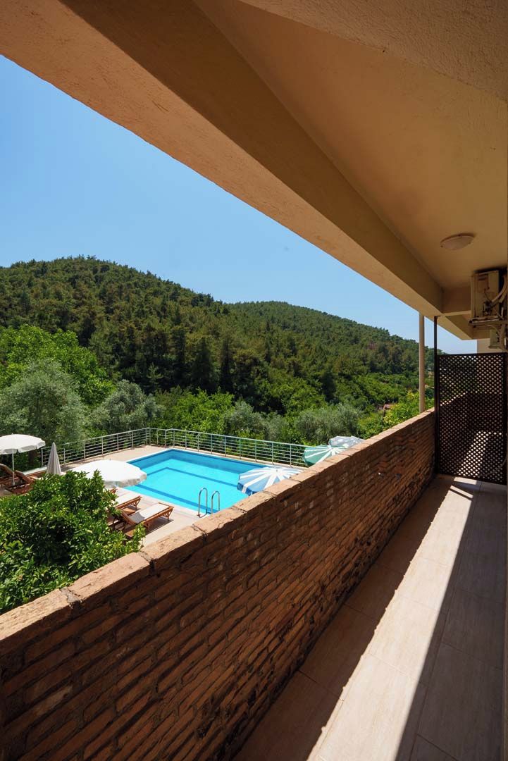 Varanda com vista para uma piscina e colinas arborizadas.