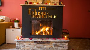 Een open haard met een bord waarop staat 'Ephesus Boutique Hotel', omringd door decoratieve objecten en een gezellige zithoek.