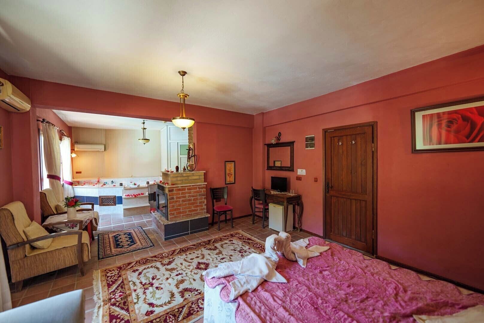 Una habitación acogedora con cama, escritorio, silla, chimenea y vistas a la cocina.