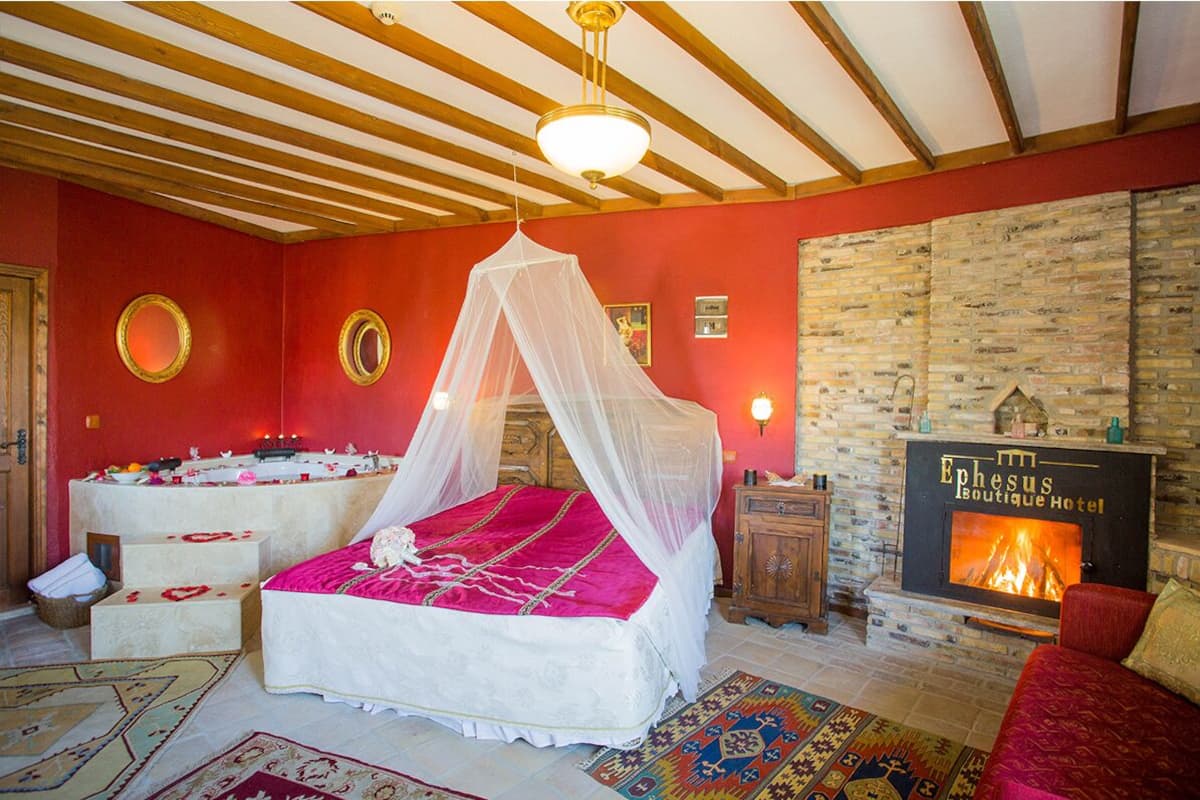 Une chambre avec un lit sous un dais, une cheminée et un mur en pierre.