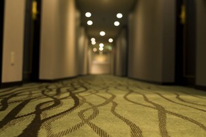 A corridor with patterned carpet and recessed lighting.