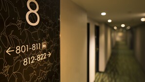 Pasillo de hotel con un cartel con el número '8' y flechas direccionales que señalan números de teléfono.