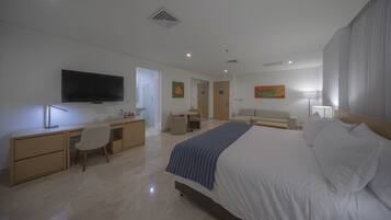Una habitación de hotel moderna con cama, escritorio, silla, televisión, sofá y un cuadro.