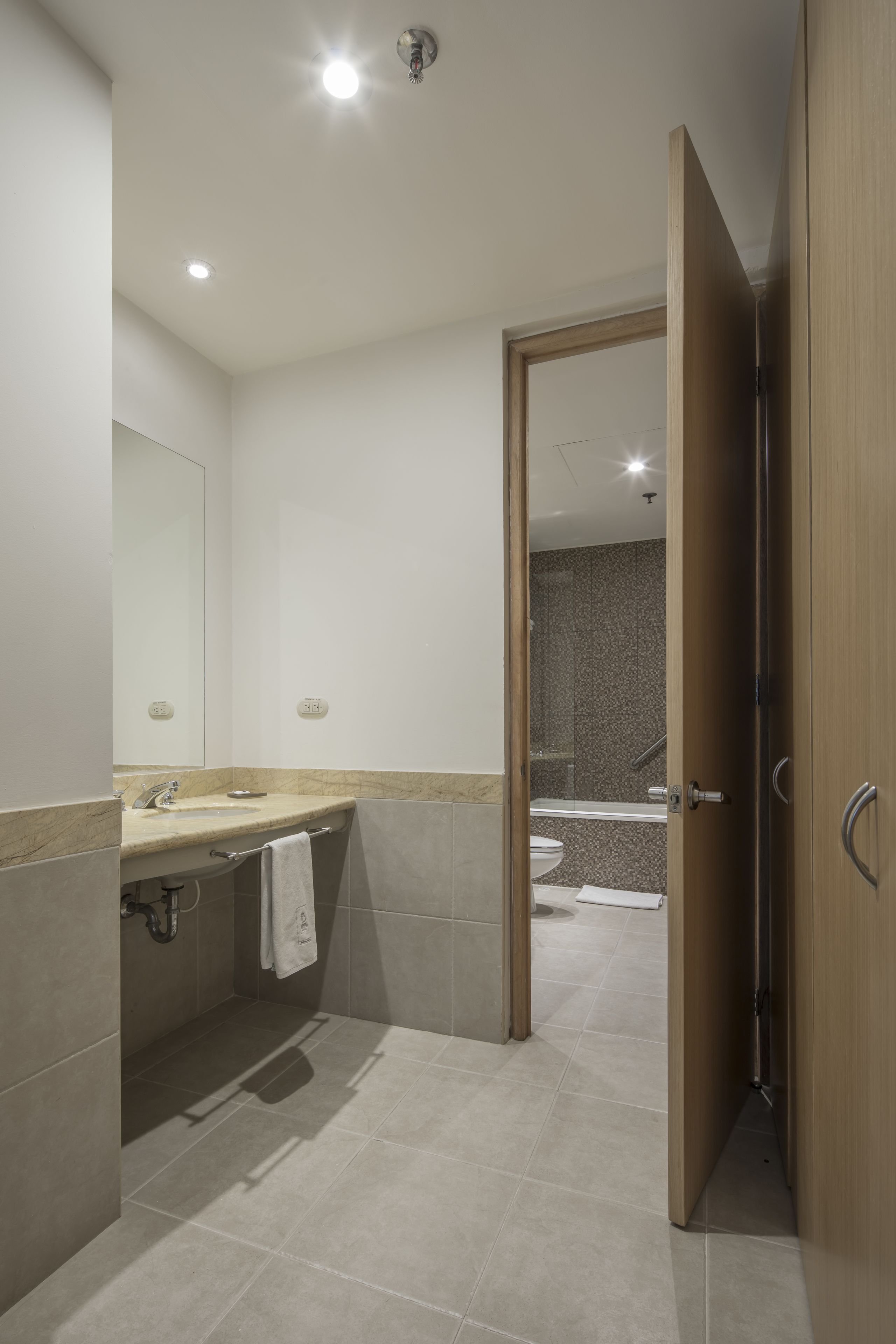 A modern bathroom with a sink, mirror, and shower area.