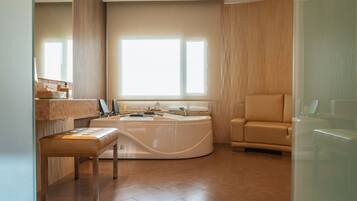 Relax in a spacious bathroom with a curved bathtub, seating area, and large window offering a view of the outside.