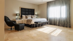 A modern bedroom with a large bed, a black leather chair, a bedside table with a lamp, and a large window with sheer curtains. - Dann Carlton Barranquilla (Barranquilla)