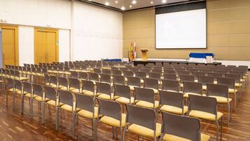 A conference room with rows of chairs, a podium, and a projection screen.