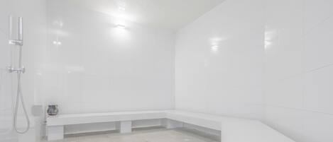 Un baño moderno con azulejos blancos, un banco y una zona de ducha.